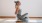 a woman  sitting on the floor mat stretching  in a lighted room